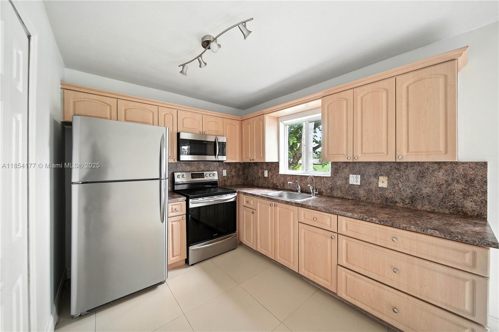 1270 Southeast 26th Street, Unit 101 Homestead, FL 33035 - Photo 5 of 18 a kitchen with stainless steel appliances granite countertop a refrigerator sink and cabinets