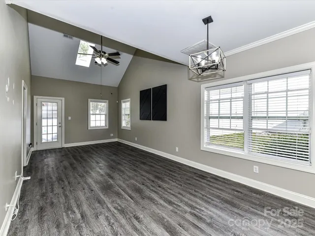 a view of an empty room with a window and wooden floor
