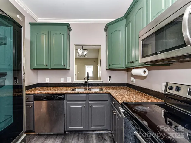 a kitchen with granite countertop a stove top oven cabinetry a sink and a microwave