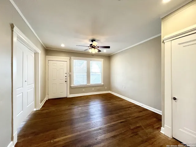a view of an empty room with wooden floor and a window