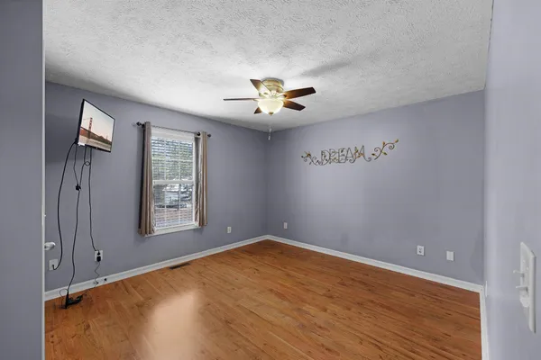 an empty room with windows and chandelier fan