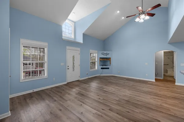 a view of empty room with wooden floor and fan