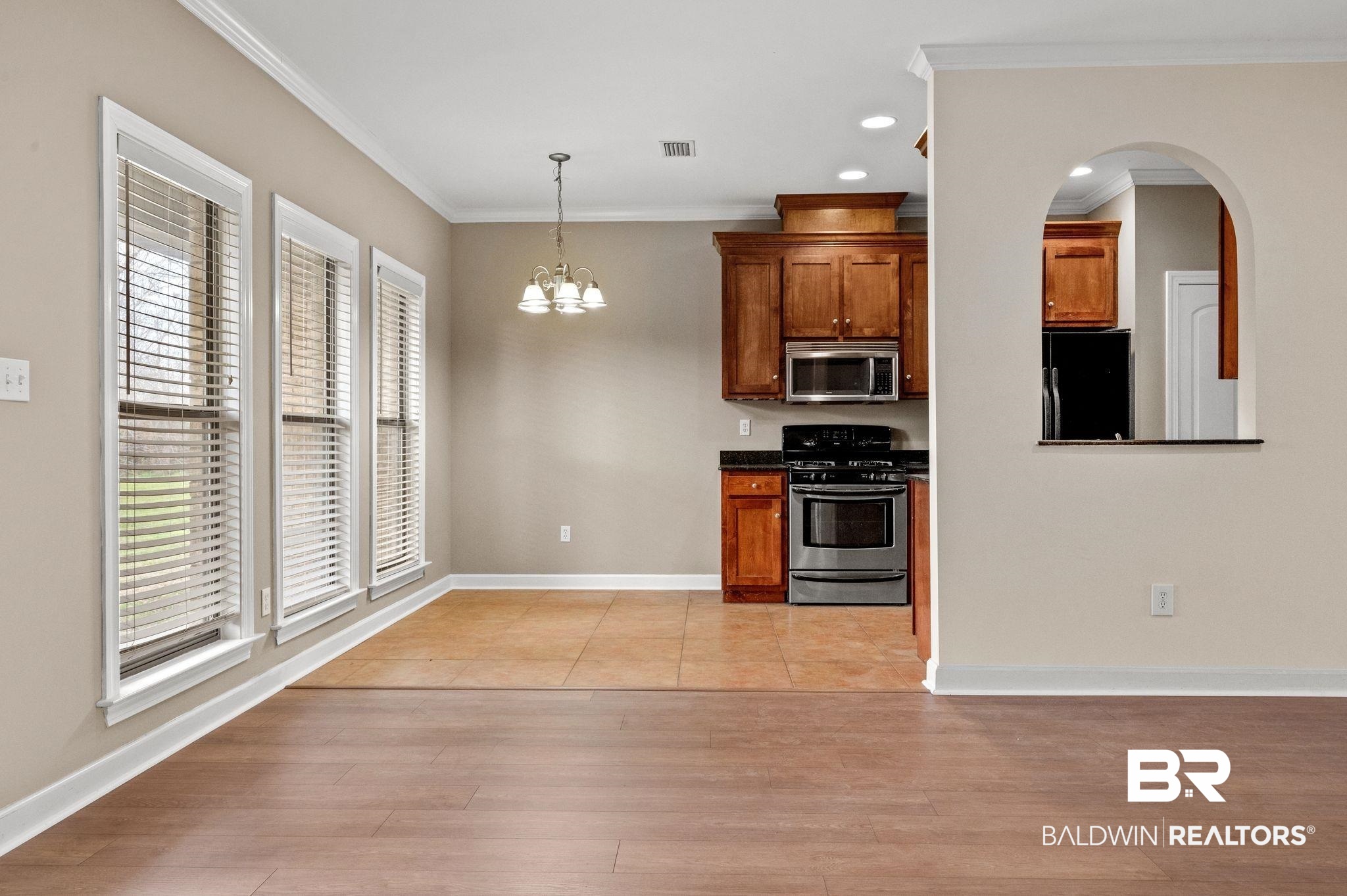 9381 Sable Court Daphne, AL 36526 - Photo 8 of 42 Kitchen with stainless steel appliances, visible vents, brown cabinetry, light wood-type flooring, and baseboards