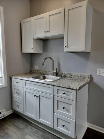 a kitchen with granite countertop white cabinets and a sink