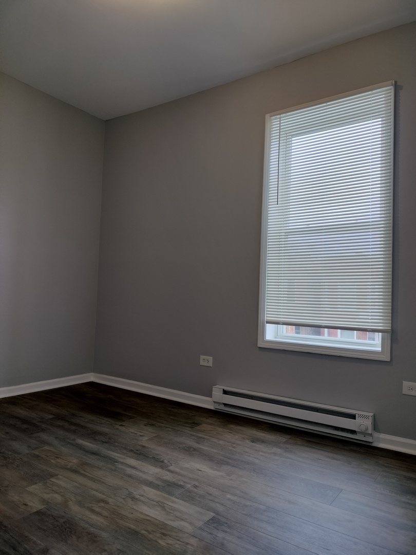 6601 South Green Street, Unit 8232 Chicago, IL 60621 - Photo 5 of 12 a view of an empty room with wooden floor and a window