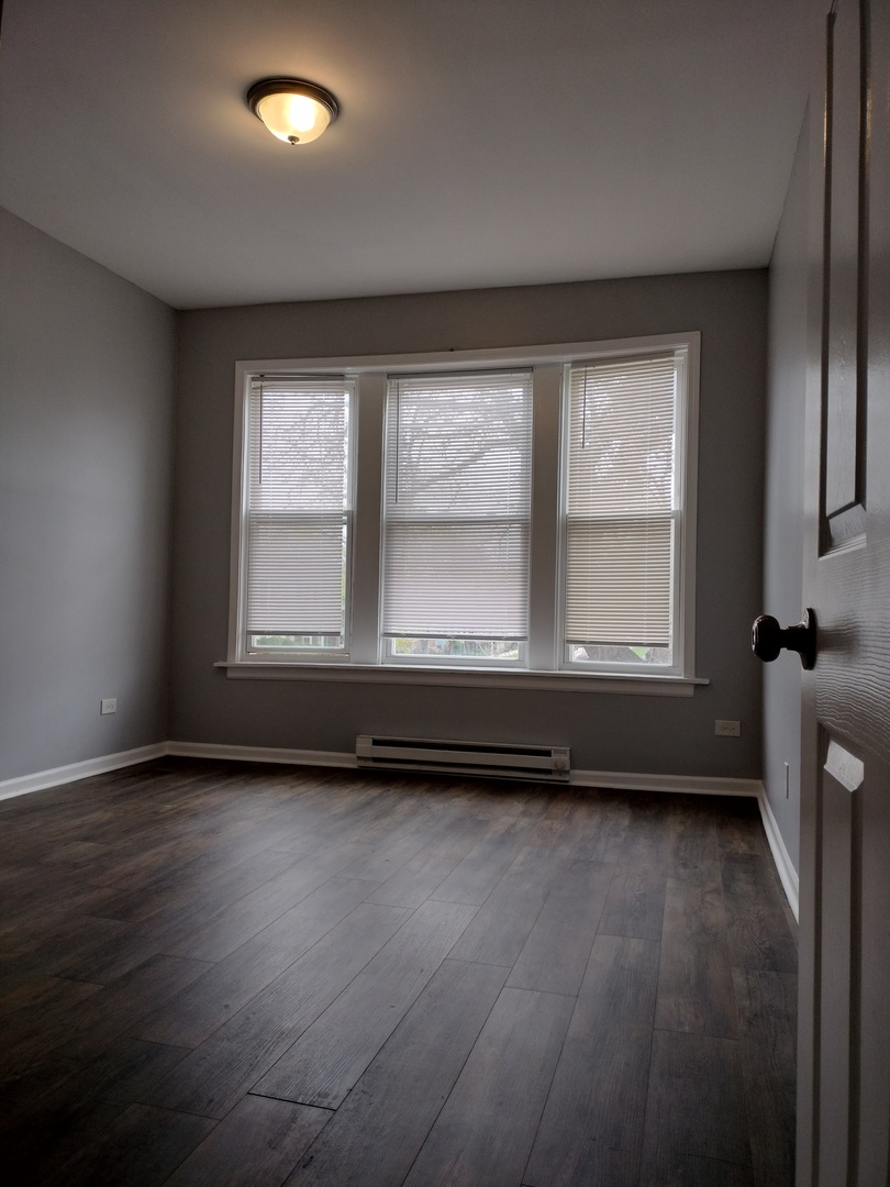 6601 South Green Street, Unit 8232 Chicago, IL 60621 - Photo 6 of 12 an empty room with wooden floor and windows
