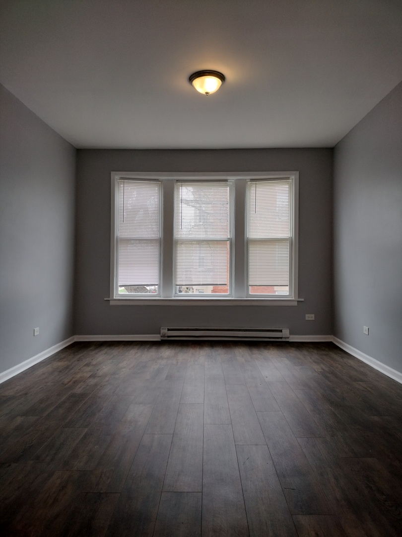 6601 South Green Street, Unit 8232 Chicago, IL 60621 - Photo 10 of 12 a view of an empty room with wooden floor and a window