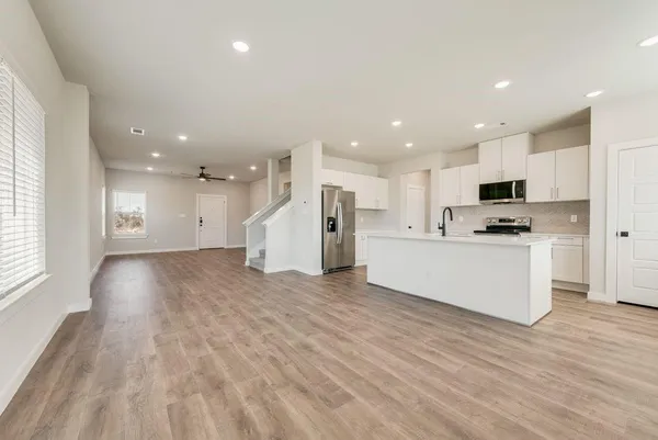a view of kitchen with stainless steel appliances granite countertop a stove top oven a refrigerator with white cabinets and wooden floor