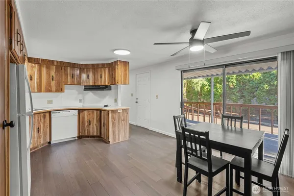 a kitchen with stainless steel appliances granite countertop a stove a refrigerator a sink a dining table and chairs with wooden floor