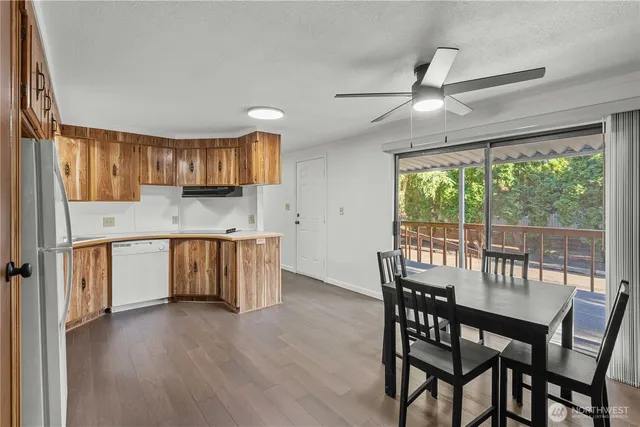 a kitchen with stainless steel appliances granite countertop a stove a refrigerator a sink a dining table and chairs with wooden floor