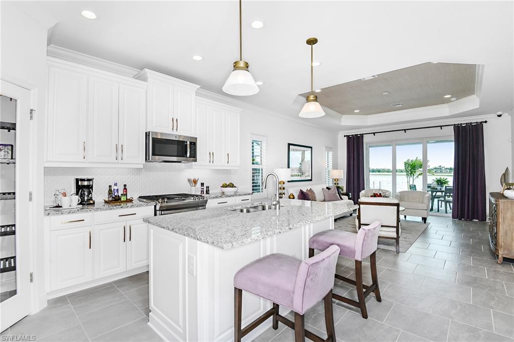 4621 Centaurus Circle Naples, FL 34120 - Photo 14 of 15 a large kitchen with kitchen island granite countertop a stove a sink a dining table and chairs with wooden floor