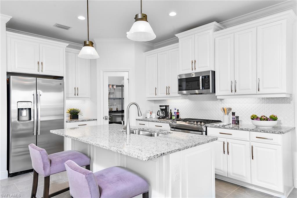 4621 Centaurus Circle Naples, FL 34120 - Photo 10 of 15 a kitchen with stainless steel appliances granite countertop a sink a microwave a refrigerator and cabinets