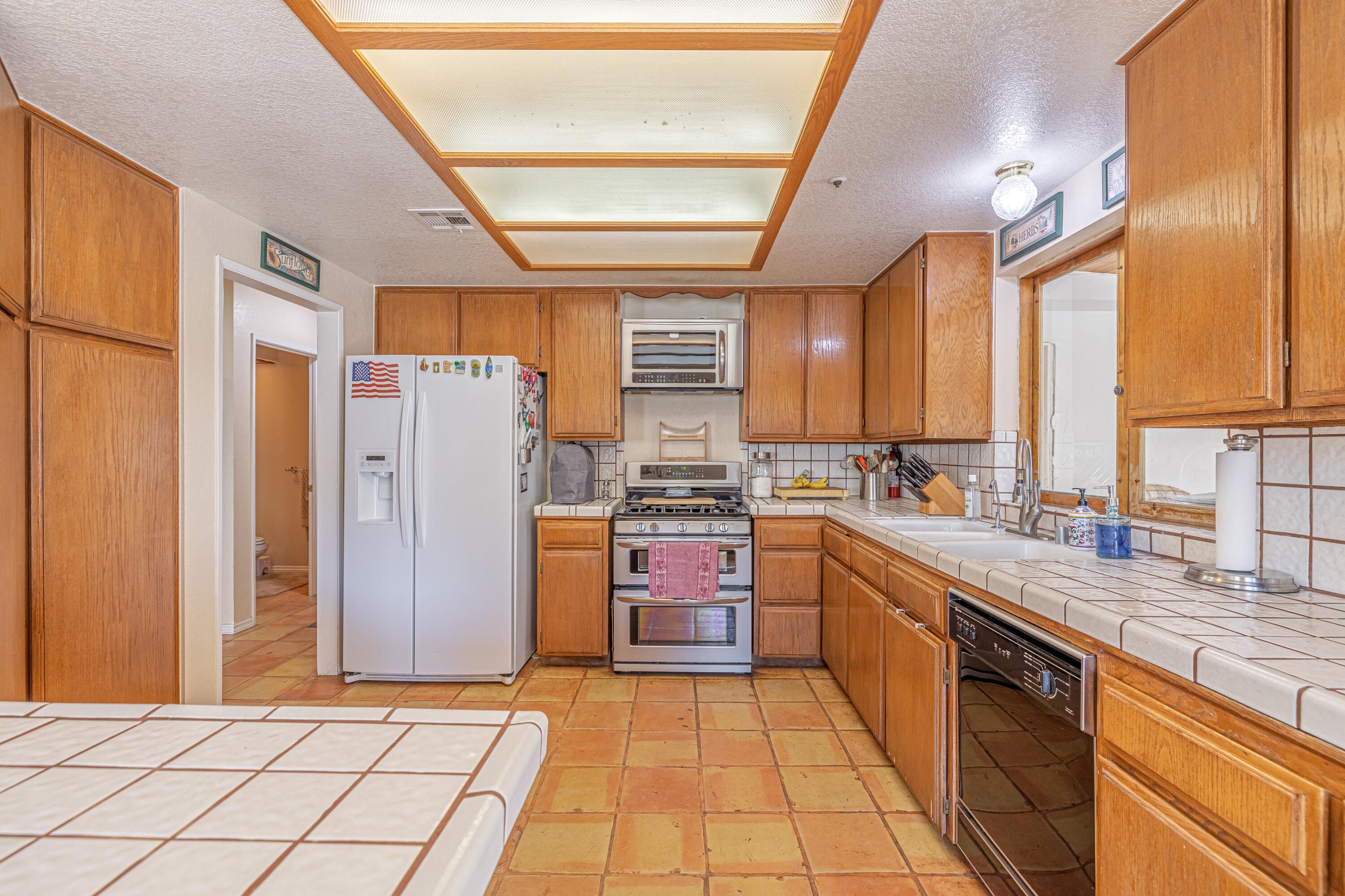 43233 55th Street East Lancaster, CA 93535 - Photo 13 of 46 a large kitchen with stainless steel appliances granite countertop a refrigerator and a stove top oven