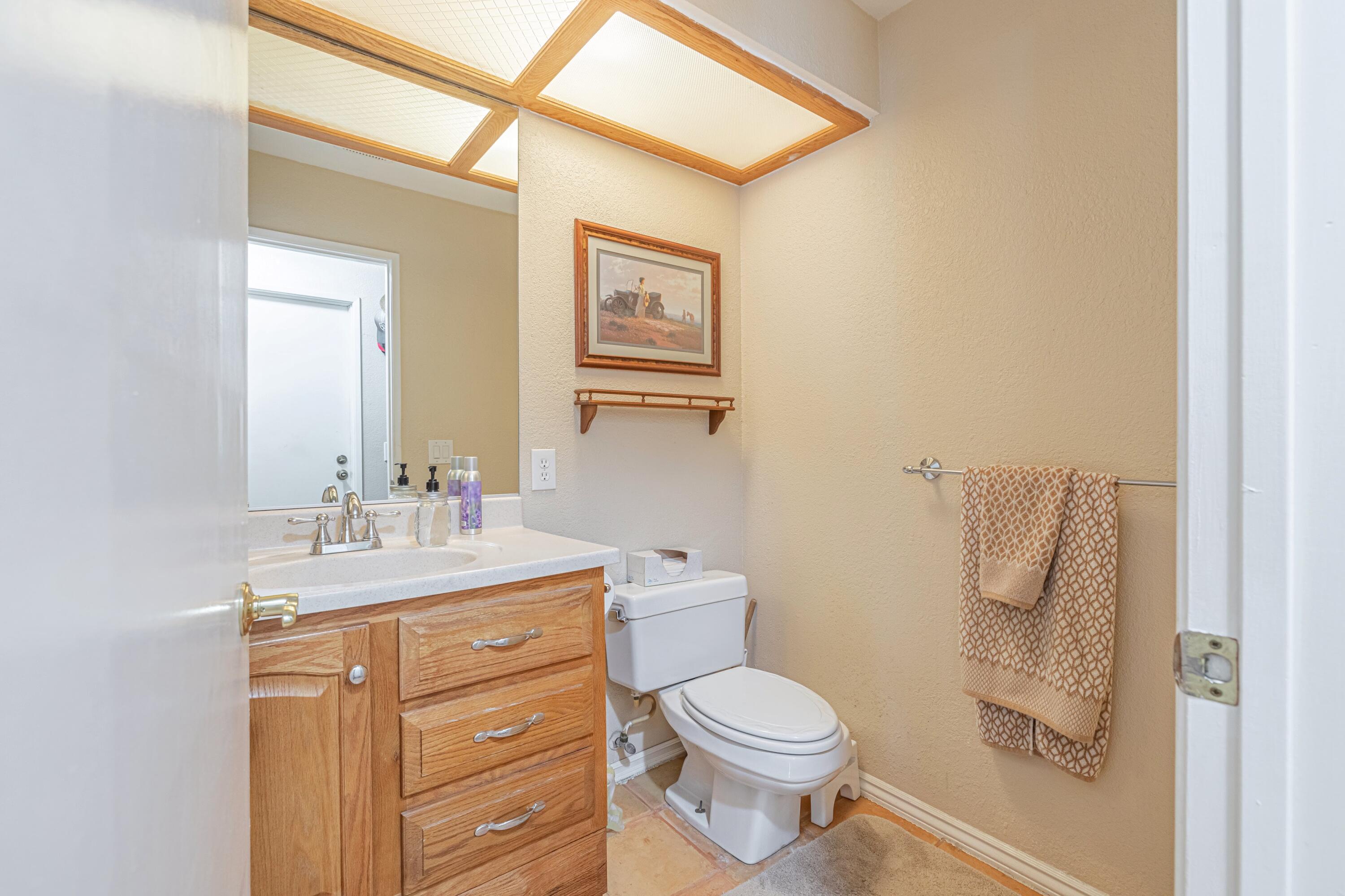 43233 55th Street East Lancaster, CA 93535 - Photo 32 of 46 a bathroom with a granite countertop toilet a sink and a mirror