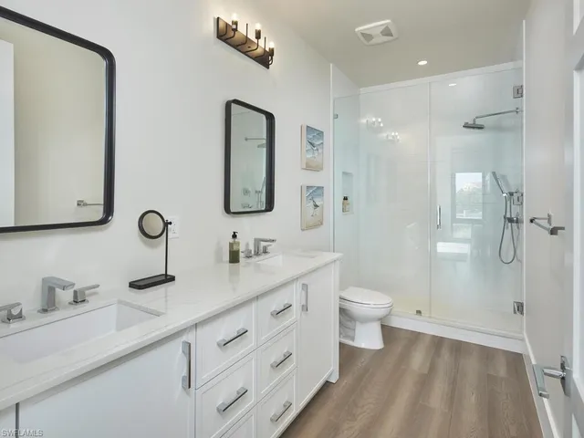 a bathroom with a double vanity sink toilet mirror and shower