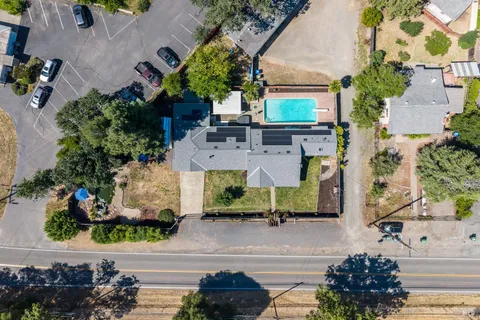 an aerial view of a house with a yard and a large tree