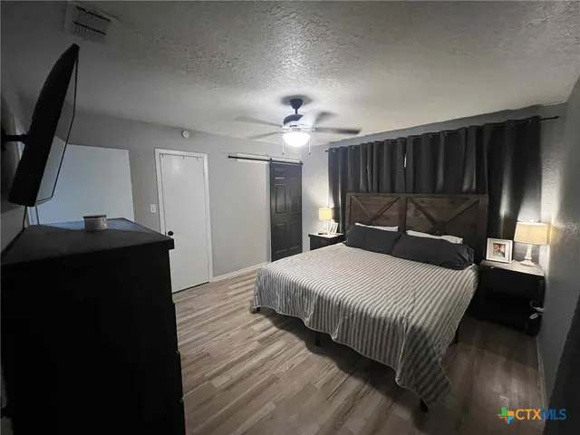 a bedroom with a bed and a flat tv screen on a dresser