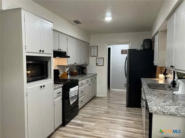 a kitchen with stainless steel appliances granite countertop a refrigerator a stove and a sink