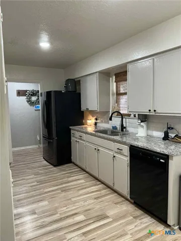 a kitchen with granite countertop a refrigerator and a sink