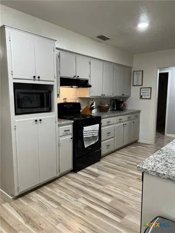a kitchen with stainless steel appliances kitchen island granite countertop a sink a stove a microwave and cabinets