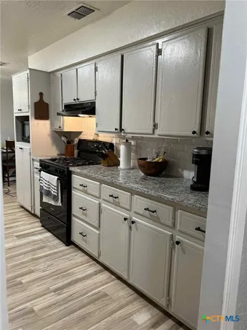 a kitchen with granite countertop white cabinets and white appliances