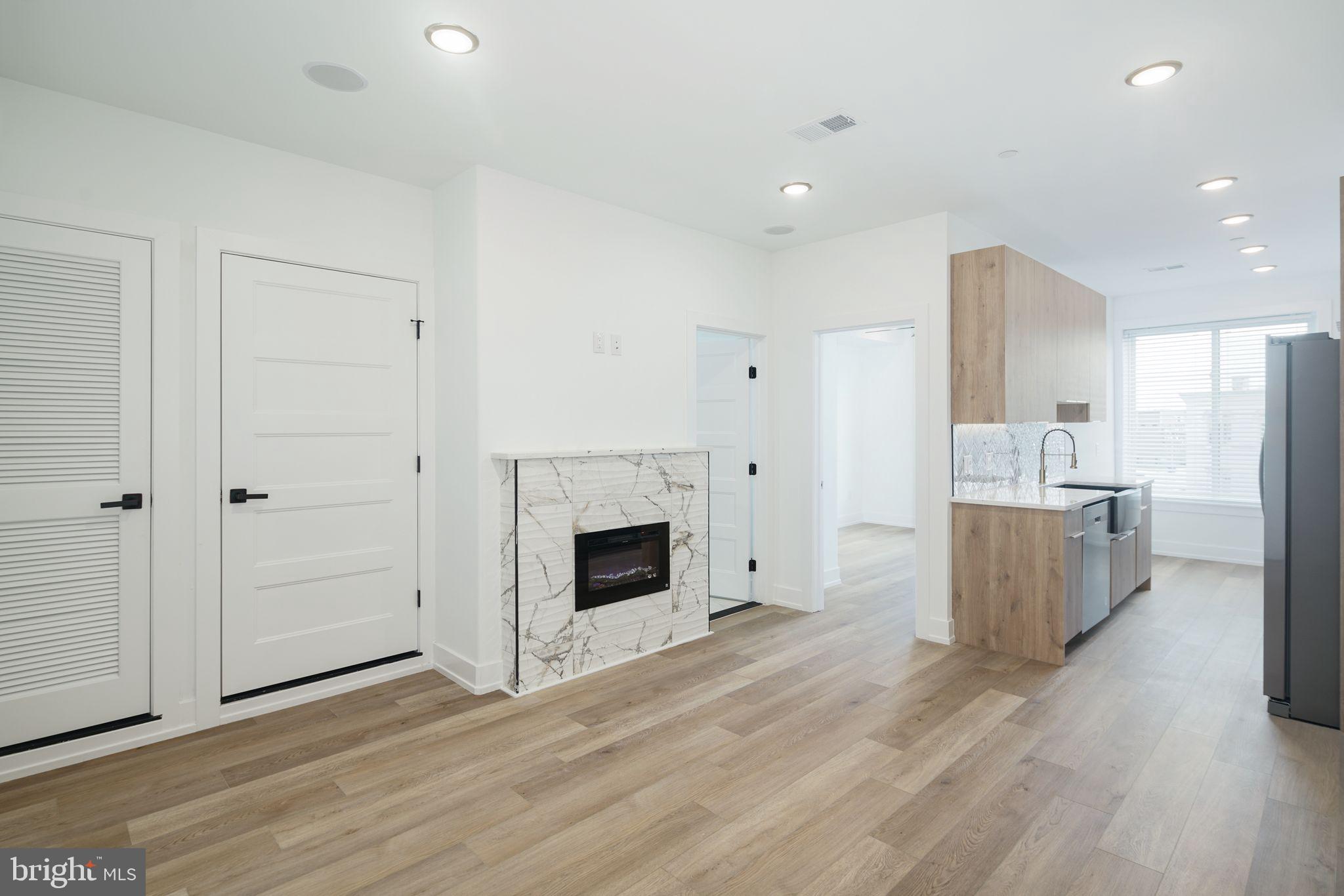 a view of kitchen and empty room with wooden floor