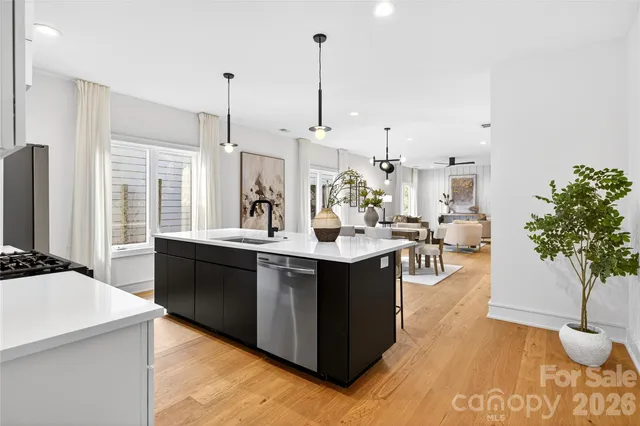 a kitchen with stainless steel appliances kitchen island granite countertop a sink a counter space and living room view