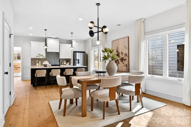 a view of a dining room and livingroom with furniture wooden floor a chandelier