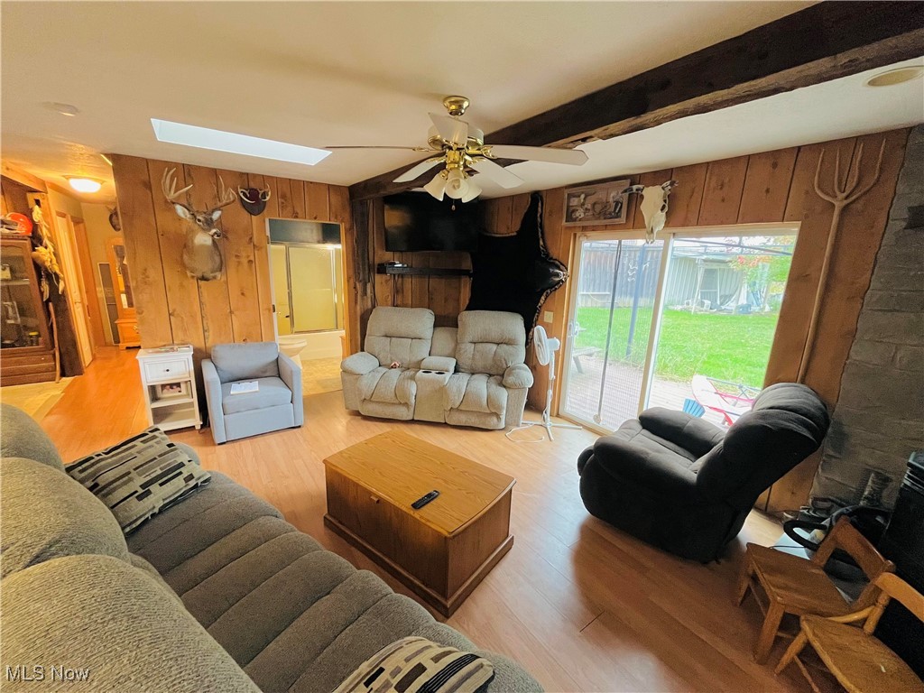 2687 Griggs Road Jefferson, OH 44047 - Photo 18 of 41 Living room featuring beam ceiling, ceiling fan, wood walls, and light hardwood / wood-style floors