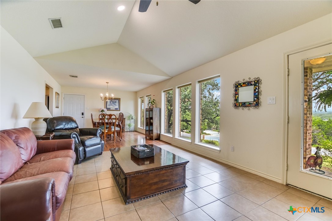60 Crazy Cross Road Wimberley, TX 78676 - Photo 5 of 20 Vast windows illuminate this open-plan living and dining area, showcasing vaulted ceilings and serene views.
