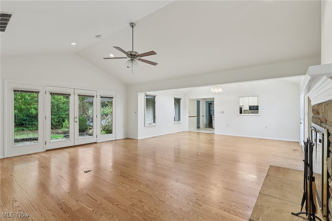 33300 South Woodland Road Cleveland, OH 44124 - Photo 15 of 50 Unfurnished living room featuring light wood-style floors, a fireplace, healthy amount of natural light, ceiling fan, and high vaulted ceiling