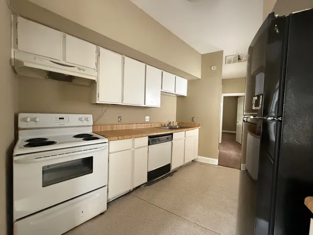 a kitchen with granite countertop white cabinets white stainless steel appliances and a refrigerator