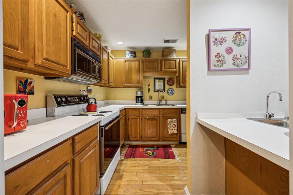 9222 Church Road, Unit 108 Dallas, TX 75231 - Photo 18 of 27 a kitchen with stainless steel appliances granite countertop a sink dishwasher stove and cabinets with wooden floor