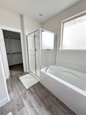 a spacious bathroom with a tub a mirror and a shower