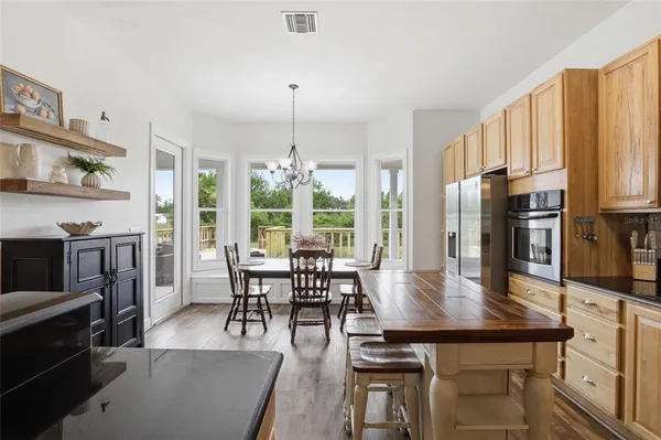 a kitchen with stainless steel appliances granite countertop a stove top oven a sink a dining table and chairs