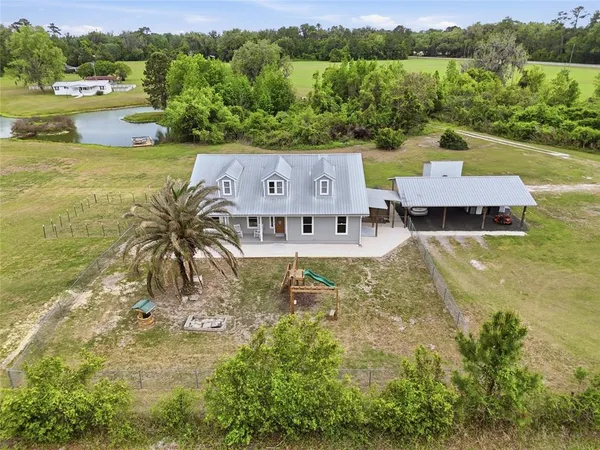 an aerial view of a house with green landscape and water view