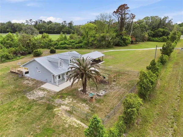 an aerial view of a residential houses with a yard and lake view