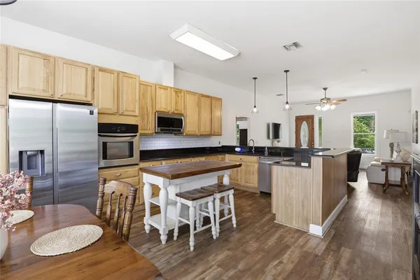 a kitchen with stainless steel appliances granite countertop a stove a sink refrigerator and white cabinets with wooden floors