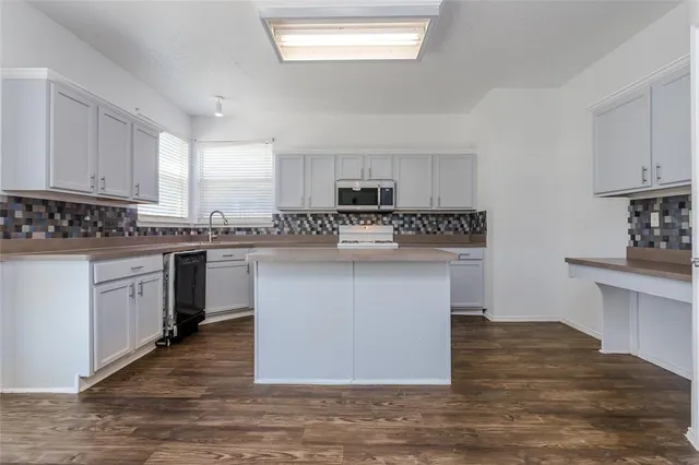 a kitchen with stainless steel appliances granite countertop a stove a sink and a microwave
