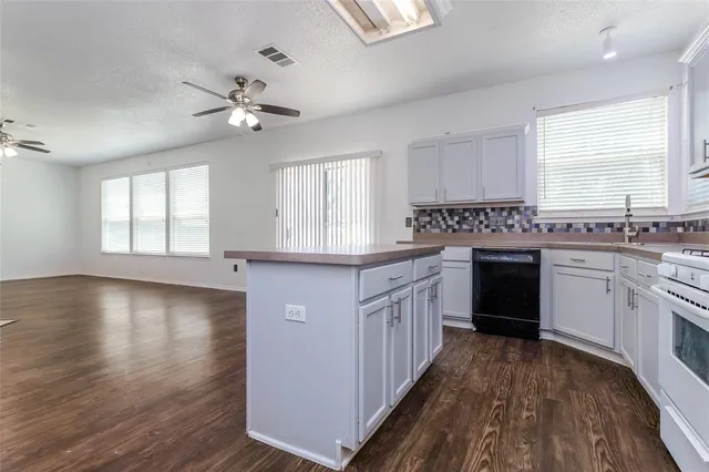 a kitchen with a white cabinets sink and dishwasher a oven with wooden floor