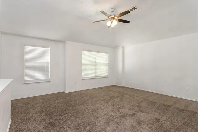 an empty room with windows and fan