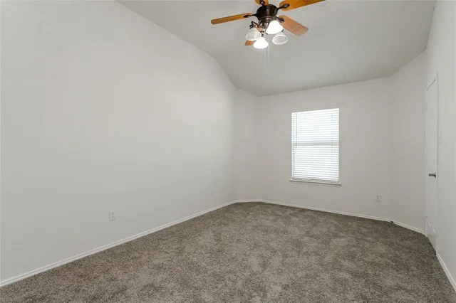 an empty room with a chandelier fan and windows