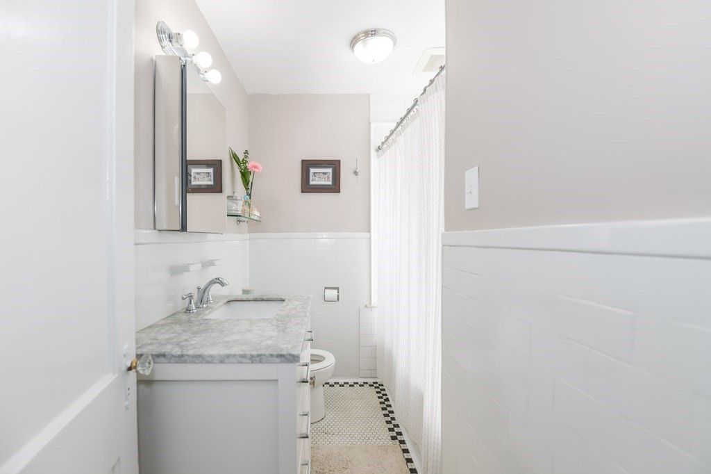 27 Fuller Road, Unit 27 Watertown, MA 02472 - Photo 9 of 13 a bathroom with a granite countertop sink a toilet and a mirror