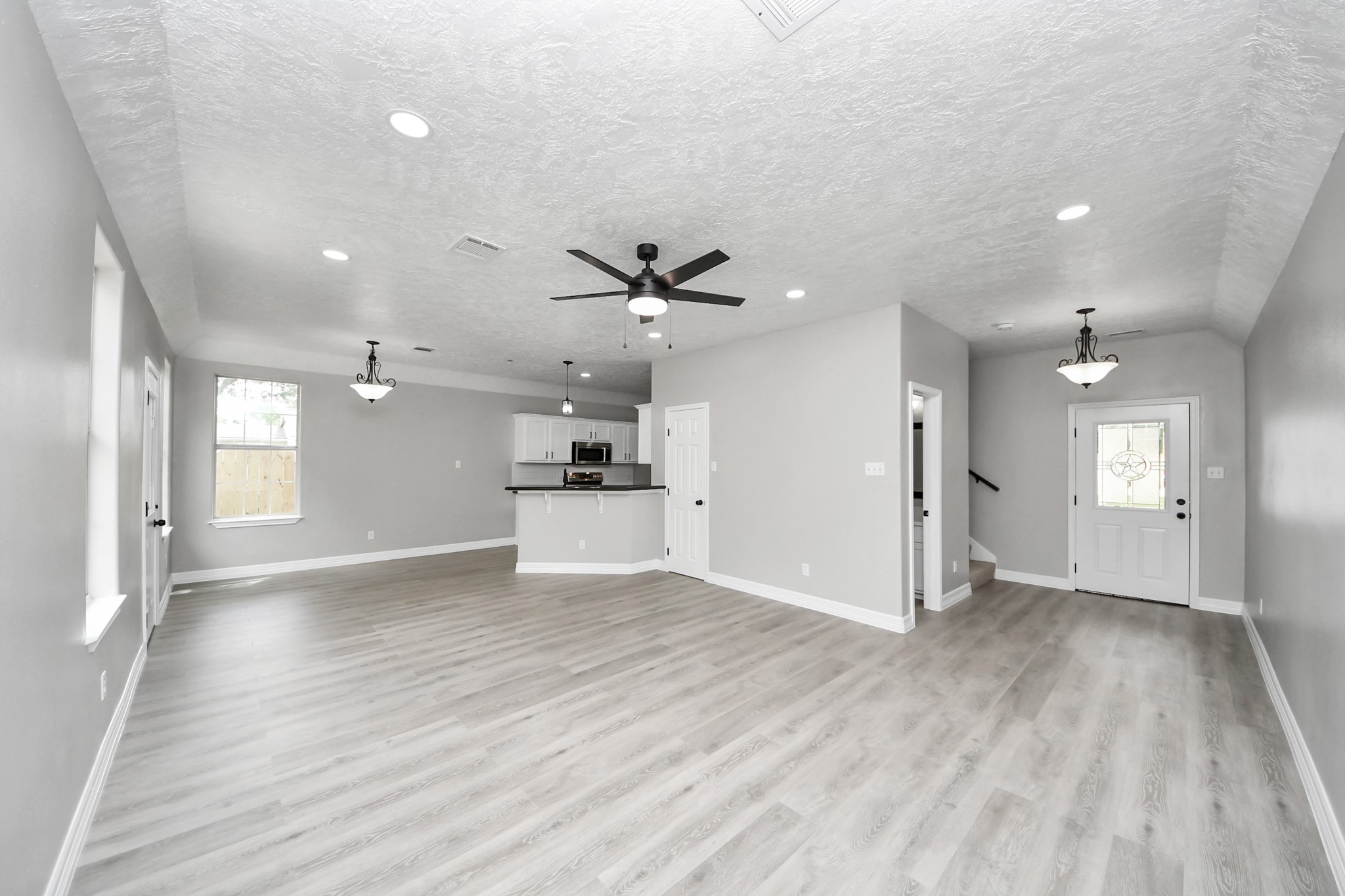 1105 East Kyle Road Clute, TX 77531 - Photo 4 of 44 This spacious, open-concept living area features modern vinyl plank flooring, neutral gray walls, and recessed lighting.