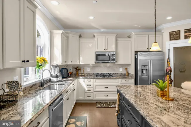 a kitchen with stainless steel appliances granite countertop a kitchen island a stove a refrigerator a oven a sink a counter and chairs