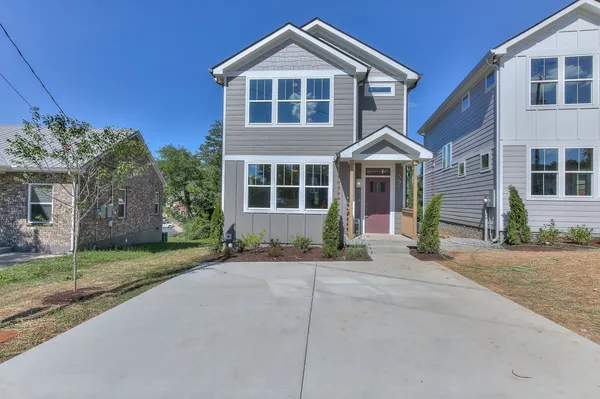 a front view of a house with a garden and trees