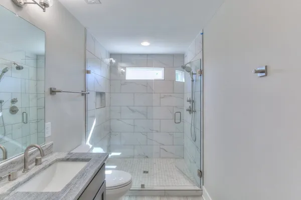 a bathroom with a granite countertop sink a toilet and shower