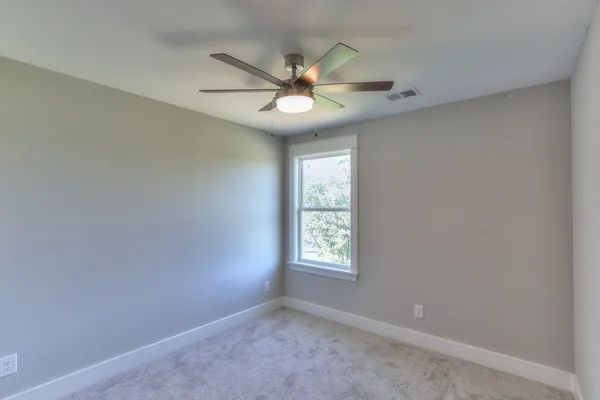 an empty room with a window and a fan