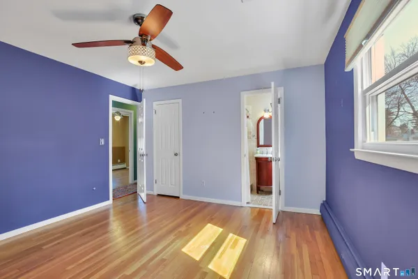 a view of empty room with wooden floor and fan