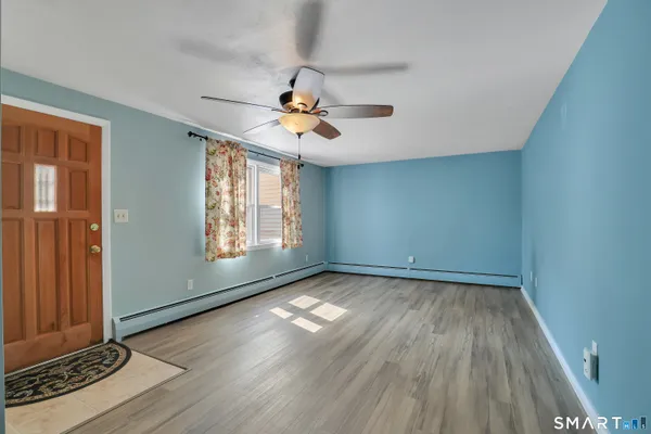 an empty room with wooden floor chandelier fan and windows